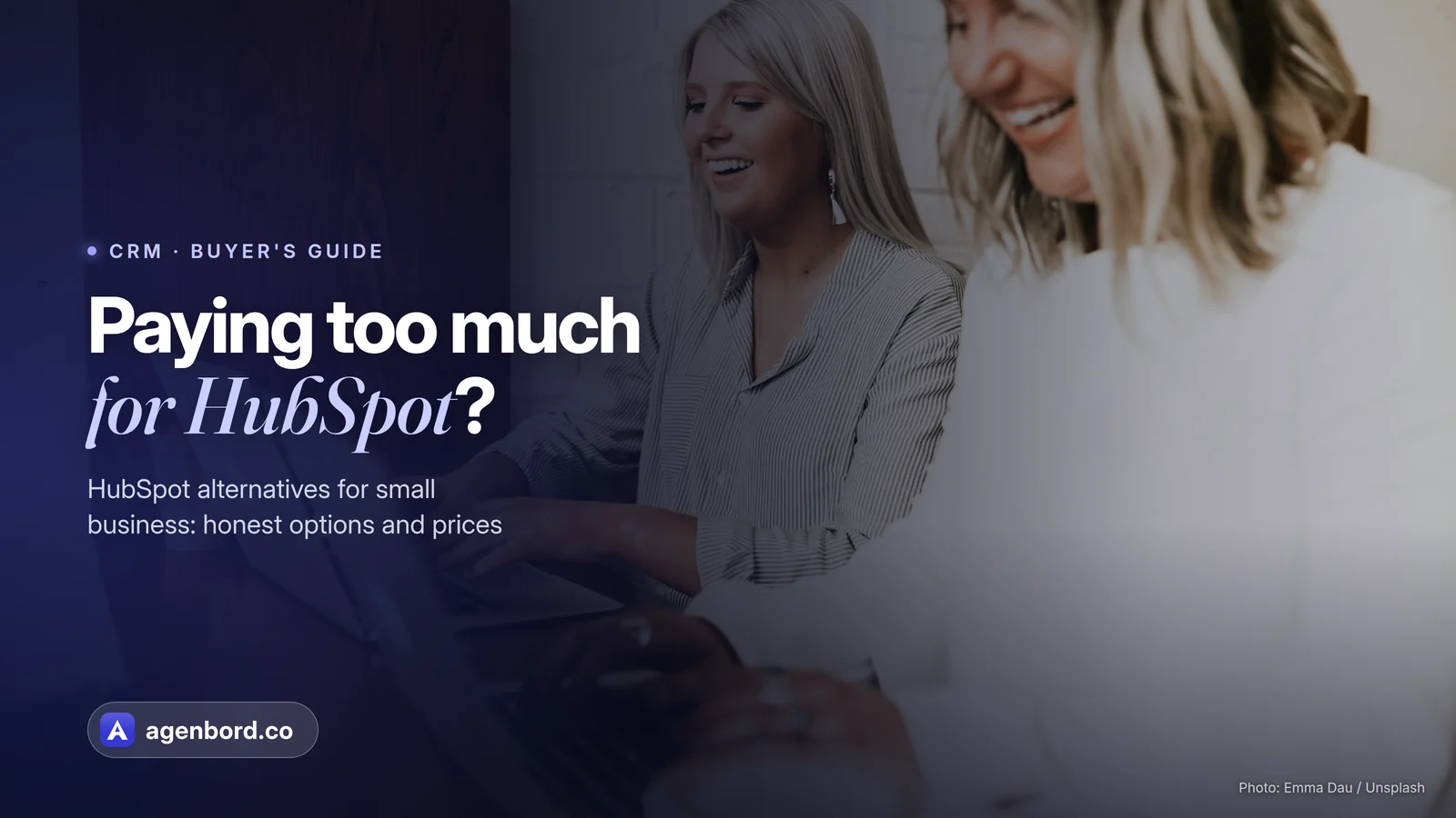 Two colleagues laughing while they work on laptops. Headline: Paying too much for HubSpot?